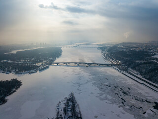 The frozen Dnieper river in Kiev. Aerial drone view. Winter frosty morning. The sun breaks through the clouds.