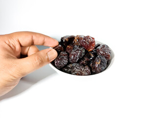 Selective focus.Hand holding dried sweet dates on bowl isolated on white background. Healthy food concept.