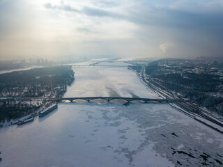 The frozen Dnieper river in Kiev. Aerial drone view. Winter frosty morning. The sun breaks through the clouds.