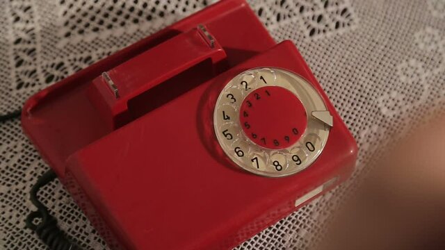 Ringing a red Rotary dial telephone. Dialing on an old rotary style telephone. Red vintage phone. retro phone ringing off the hook. Answering old rotary telephone, talking, having a conversation.
