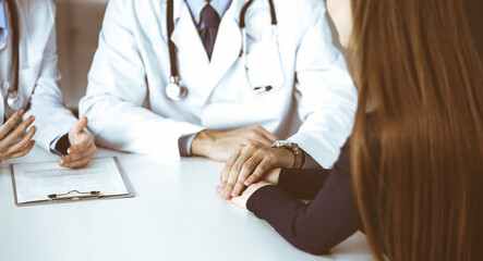 Unknown man-doctor reassuring his female patient, close-up. Two physicians consulting and giving...