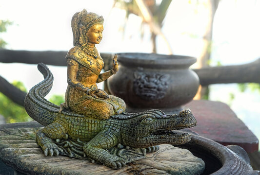 old deity sculpture in garden Buddhist temple. religion art national concept. Buddhism culture symbol. relax spiritual travel. stone figure of women Asian deity and crocodile