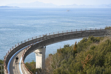 日本の来島海峡大橋にある自転車道でサイクリングを楽しむ人　ナショナルサイクルルート「しまなみ海道サイクリングロード」