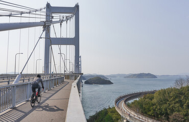 日本の来島海峡大橋にある自転車道でサイクリングを楽しむ人　ナショナルサイクルルート「しまなみ海道サイクリングロード」