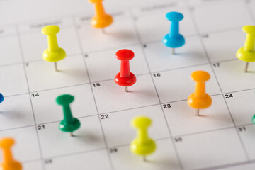 Everyday plans concept. Cropped closeup view photo of many lot pushpins attached to the calendar with selected dates