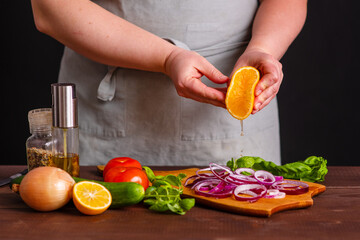 The cook pickles the red onion with lemon juice, squeezing it onto the chopped onion. Cooking a burger.