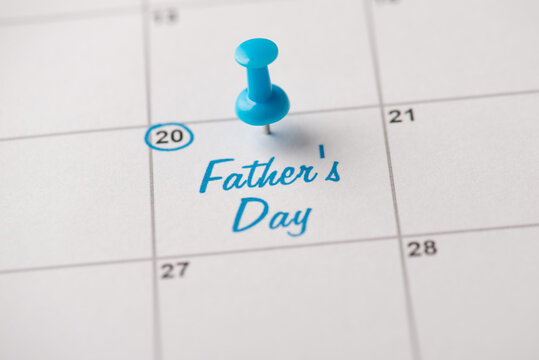 Happy Father's day concept. Cropped close up view photo of light blue pushpin attached to calendar with congrats text