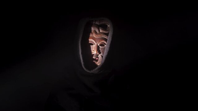 Scary monster in the dark. Creepy priest horror scene, mysterious acolyte in the black background. Darkness and fear concept, voodoo mask, weird warlock.