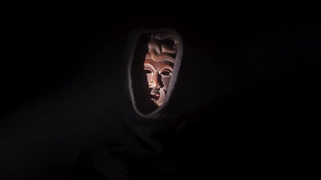 Scary monster in the dark. Creepy priest horror scene, mysterious acolyte in the black background. Darkness and fear concept, voodoo mask, weird warlock.