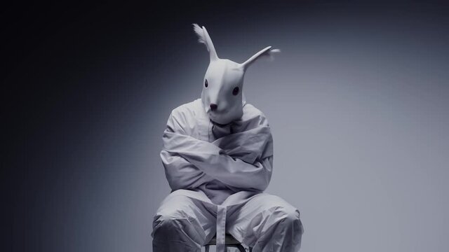 Madness and mental illness concept. Scary, crazy person in animal mask tied in a white room. Nightmare, psychosis. Paranoia and depression concept, isolated madman.