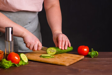 The chef cuts fresh vegetables on a wooden board. Cooking a burger.