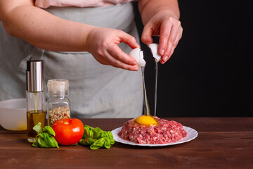 The cook adds an egg to the fresh mince for the burger. Cooking a burger. Frozen egg movement in flight