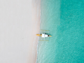 Aerial top down view of white sand beach with a traditional philippine boats beached on it - 415540786