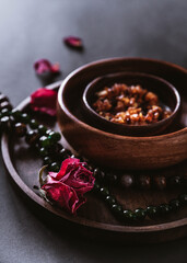 dry roses on wooden plates. three wooden plates on a black background. still life with wooden dishes, dried flowers and jewelry
