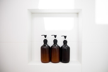 Brown soap bottles in bathroom shower wall 