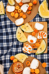 Summer picnic concept. A piece of bread spread with soft cheese and apricot wedges. Delicious dessert with yellow watermelon or melon.