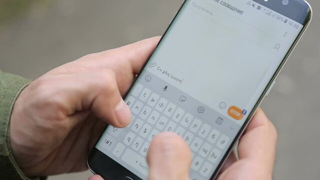 Writes a message on a mobile phone. Phone in his hands.  