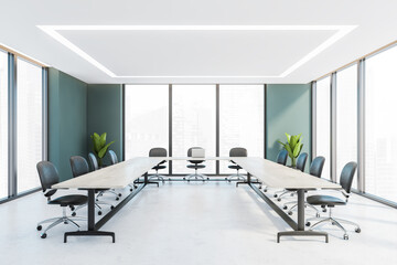 Office conference room with white wooden u-shape table and leather chairs, windows