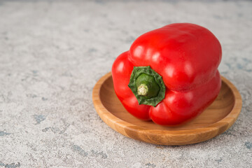 Fresh juicy red bell pepper in a plate on a concrete background,