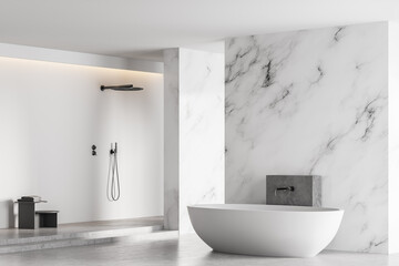 White bathtub and shower in light marble bathroom with window