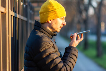 Portrait of modern man talking on the phone with hands free in the street. 