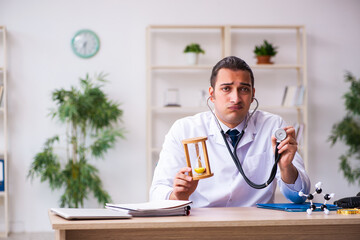 Young male doctor in time management concept