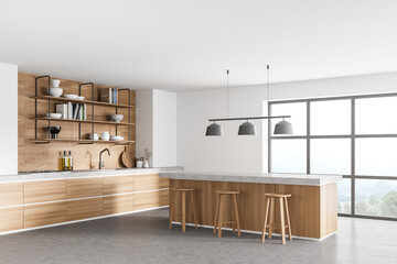 White modern kitchen near window. Dining area with wooden countertop. Concrete floor. Panoramic windows.