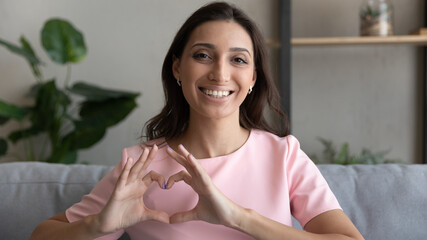 Happy arabic woman vlogger look at camera show finger heart demonstrate gratitude to audience....