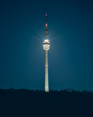 Stuttgart Television Tower (Fernsehturm) casting light rays against starry night sky