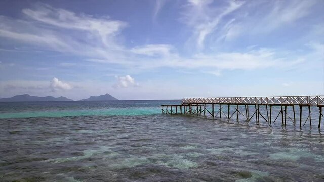 calming waves of the Semporna Celebes Sea Ocean near the wooden pier during a warm sunny morning with beautiful sky.