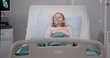 Girl suffering from pneumonia lying in a hospital bed with oxygen mask
