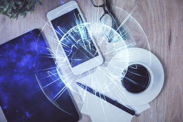 Double exposure of business theme hologram over desktop with phone. Top view. Mobile international...