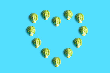 Brussels sprouts seamless pattern. Pop art cabbage pattern. Abstract background with small cabbage. Colorful vegetable pattern of green cabbage. Heart-shaped cabbage. Vegan love.