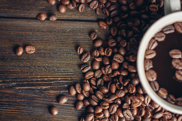 aromatic drink in a cup and coffee beans scattered on a wooden background