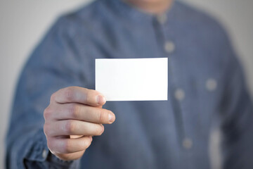 A man holds a white business card. A paper in the hands of a man. Prepared for your text. Isolated on a gray background