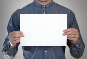A man holds a white piece of paper. A flyer in the hands of a man. Prepared for your text. Isolated...