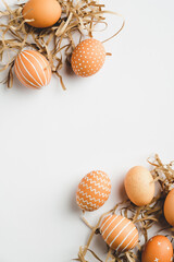 Frame of Easter eggs and straw on white background. Flat lay, top view, copy space. Easter vertical banner mockup.