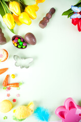 Easter set with colorful eggs, carrots, candy, cupcake. Top view. Copy space.