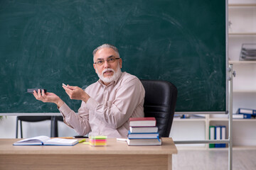 Old male teacher sitting in the classroom