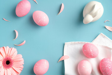 Easter flat lay composition. Pink Easter eggs, bunny, spring flowers, petals on turquoise background. Happy Easter concept.