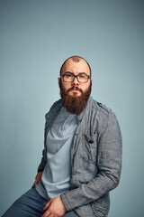 Obraz premium lifestyle successful young man with glasses , beard, fashionable denim jacket looking forward,male portrait in the Studio on a uniform background.