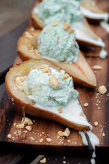Bbq dessert: baked barbecue pear with pistachio ice cream, peanuts, almonds and honey. Vertical image.