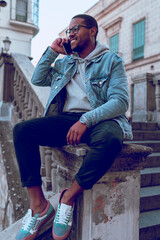 black boy sitting on ladder using mobile phone