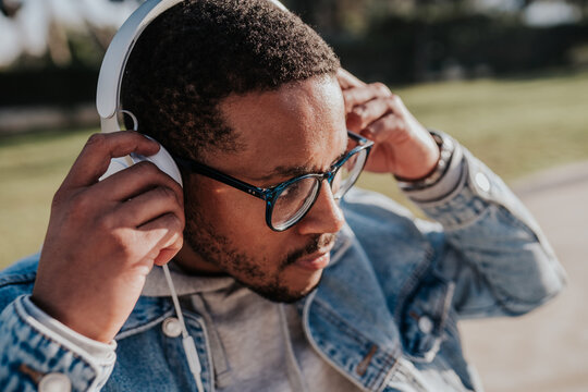 black boy in park listening to music with headphones