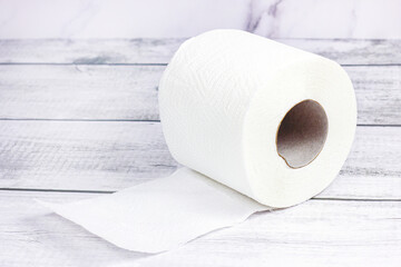White toilet paper roll on light gray wooden background.