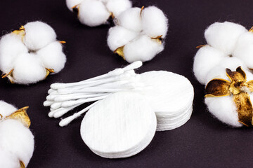 White soft cotton pads and sticks for hygiene and healthcare on black background.