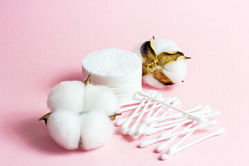 White soft cotton pads and sticks for hygiene and healthcare on light pink background