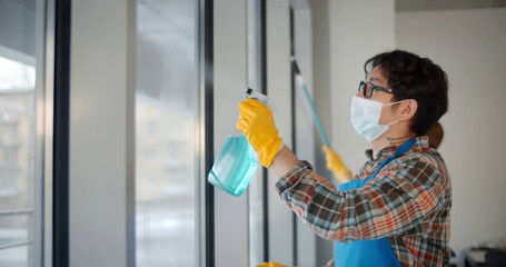 Team of commercial cleaners in safety mask working in office cleaning windows
