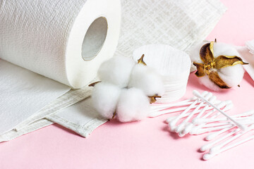 White soft cotton pads and sticks for hygiene and healthcare on light pink background.