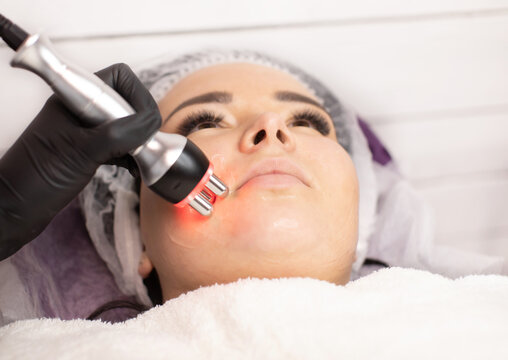 Hardware cosmetology. Closeup picture of happy young woman getting rf lifting procedure in a beauty parlour. Radio lifting.